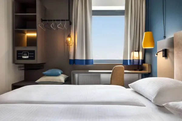 Nowoczesny pokój hotelowy z wygodnym łóżkiem, biurkiem i oknem. Zastanawiasz się, ile kosztuje nocleg w Krakowie?