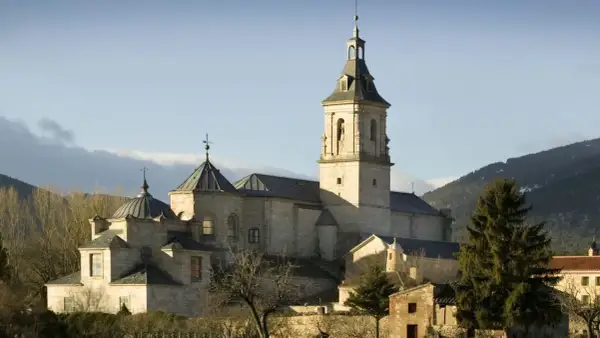 El imponente monasterio del Paular se alza bajo un cielo azul, con sus cúpulas y campanario de piedra bañados por el sol.