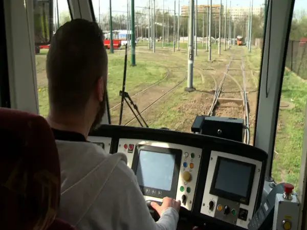 Mężczyzna za sterami tramwaju, być może uczestnik darmowego kursu na maszynistę, obserwuje tory.