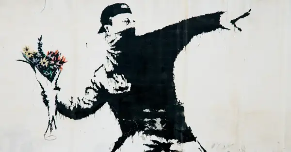 Czarny mural przedstawia zamaskowanego mężczyznę w czapce, rzucającego bukiet kolorowych kwiatów. To najładniejszy rysunek na świecie, pełen nadziei i buntu.