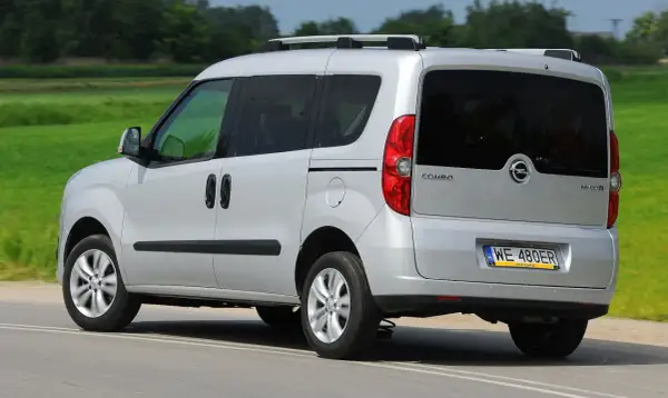 Srebrny Opel Combo C w ruchu, z tyłu widoczny bagażnik dachowy i przyciemniane szyby.