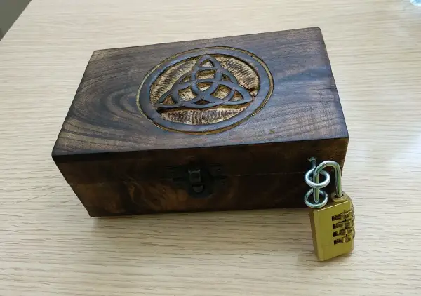 Caja de madera con símbolo celta y candado de combinación, lista para un escape room matematicas.