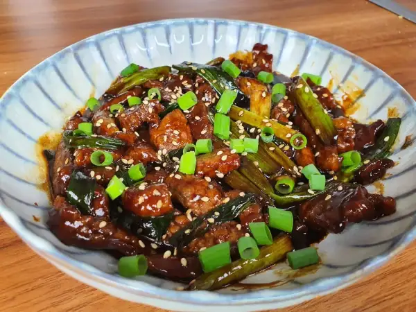 Un plat appétissant de boeuf aux oignons, garni de graines de sésame et d'oignons verts frais.