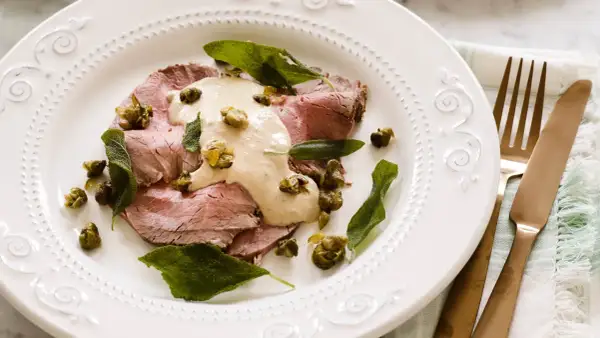 Skivor av tunt skuret kött toppas med en krämig tonfisksås, kapris och salviablad. En elegant portion av vitello tonnato.