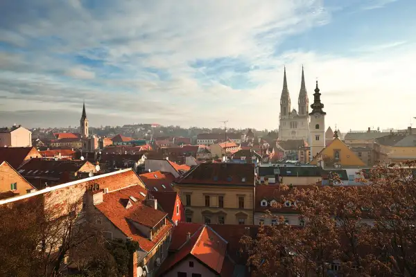 Vy över Zagreb, kroatiens huvudstad, med dess karakteristiska röda tak och imponerande katedral som reser sig mot en molnig himmel.