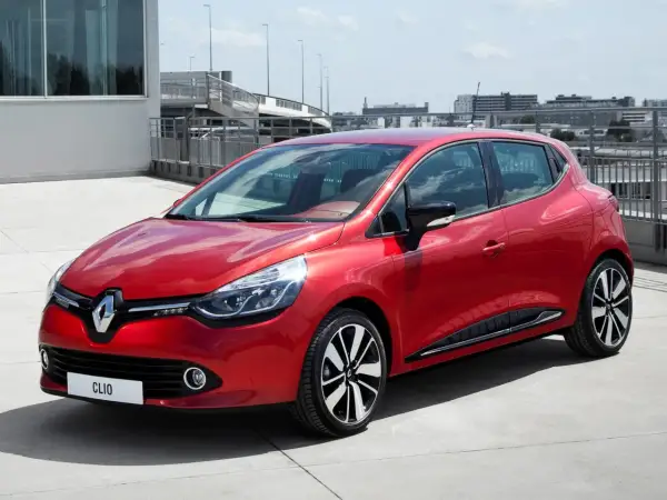 Czerwone Clio 4 RS błyszczy na betonie, gotowe do dynamicznej jazdy.