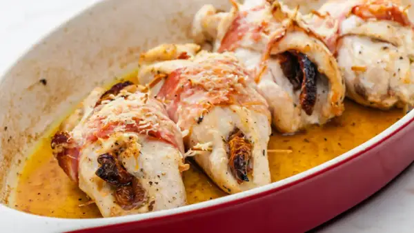 Pyszne roladki z kurczaka zawinięte w boczek, zapieczone z suszonymi pomidorami i posypane parmezanem, w sosie własnym.