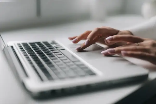 Dłonie z różowym lakierem na paznokciach pracują na touchpadzie laptopa. To nowy model sd-3, który ułatwia codzienne zadania.