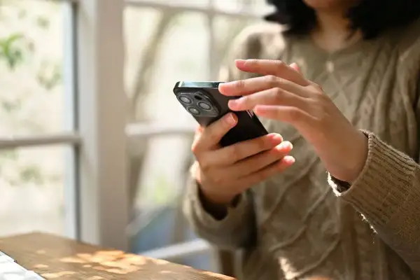 Dłonie kobiety trzymają smartfon, korzystając z aplikacji do zdjęć paszportowych.