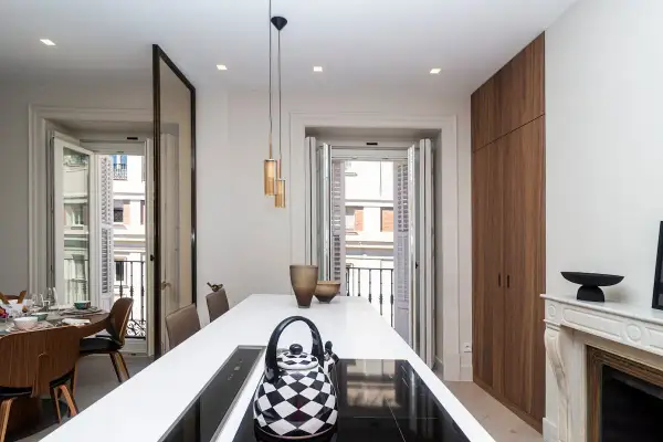 Cocina moderna con isla blanca, tetera a cuadros y vistas a balcón. Un buen lugar para vivir, pero ¿cuánto cuesta un alquiler en Madrid?