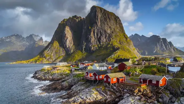 Traumhafte norwegen route 2 wochen: Rote Fischerhäuser am Fuße steiler Berge an der Küste.
