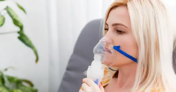 Kobieta z maską nebulizatora, wdychająca sól fizjologiczną.