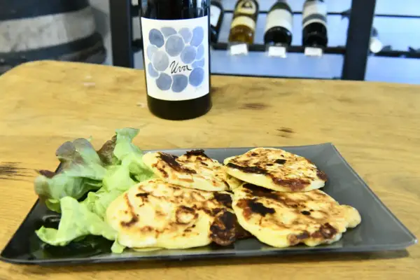 Assiette de migliacci dorés, accompagnés de salade verte, avec une bouteille de vin en arrière-plan. Une recette simple et savoureuse.