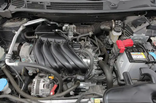 Silnik Nissan Qashqai J10, z widocznym kolektorem dolotowym, akumulatorem i alternatorem.