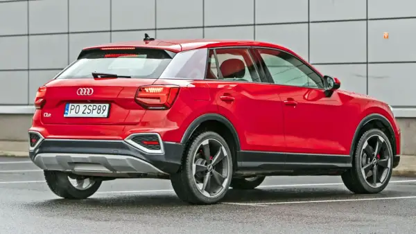 Czerwone Audi Q2 z polskimi tablicami PO 2SP89. Kompaktowy SUV, którego wymiary sprawiają, że jest idealny do miasta.