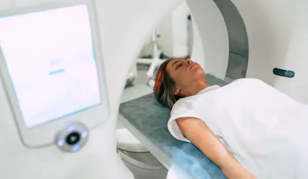 Kobieta leży na stole do rezonansu magnetycznego. Czerwone linie lasera wskazują obszar badania. Ważne są rezonans magnetyczny przeciwwskazania.