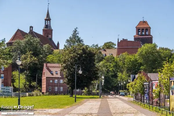 Tczew atrakcje: zabytkowy kościół, urokliwe kamieniczki i zielony park. Spacerowicze cieszą się słonecznym dniem.