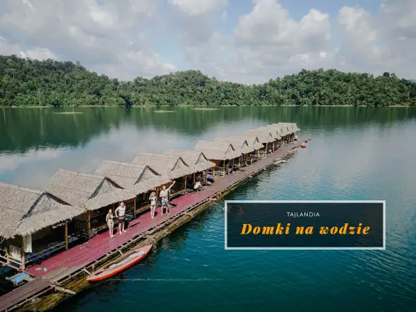 Domki na wodzie w Khao Sok, Tajlandia. Grupa ludzi relaksuje się na drewnianym pomoście, otoczonym bujną zielenią i spokojną wodą.