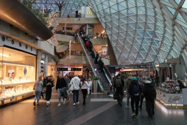 Ludzie w centrum handlowym, schodzą i wchodzą na ruchome schody. Czy 6 stycznia są otwarte sklepy? Widać sklepy z biżuterią i jedzeniem.