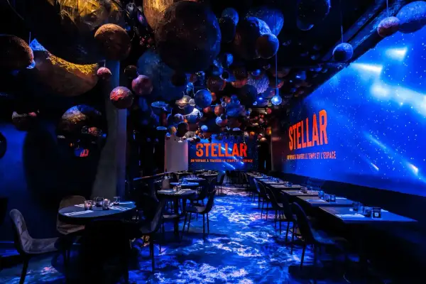 Décoration de restaurant "STELLAR" avec des planètes suspendues, évoquant un voyage **éphemère stellaire**. L'ambiance est cosmique et immersive.