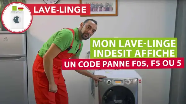 Un homme en salopette rouge devant un lave-linge Indesit 9 kg qui affiche un code panne F05.