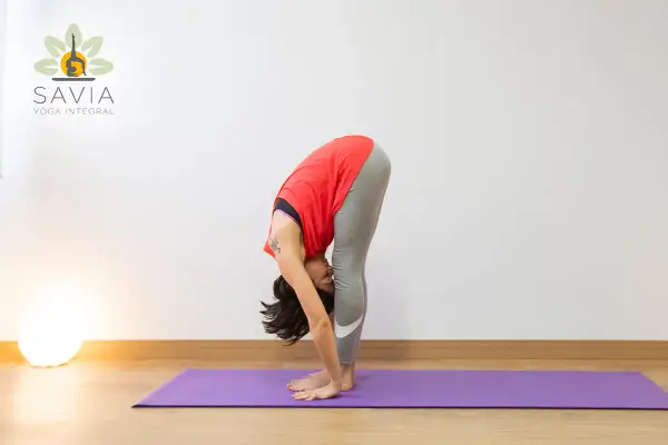 Mujer en postura de Uttanasana yoga, estirando su cuerpo hacia abajo.
