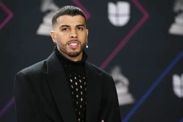 Rauw Alejandro, de Puerto Rico, posa con un traje negro y un suéter de red.