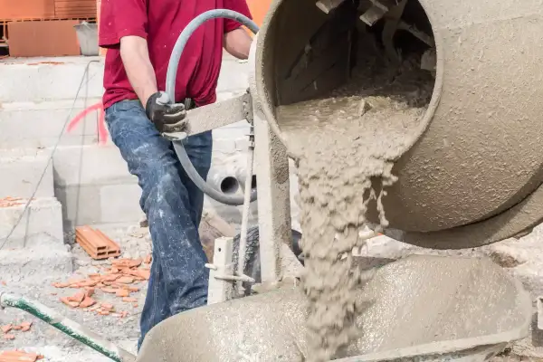 Robotnik miesza chudy beton, dbając o właściwe proporcje składników.