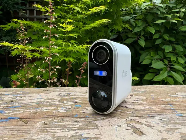 Une caméra de surveillance blanche avec une lumière bleue allumée, posée sur un banc en bois. Un moyen simple pour savoir si une caméra fonctionne.