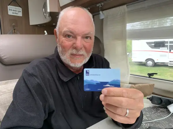 Man håller upp ett AutoPASS-kort för färjor, redo för bila i Norge.