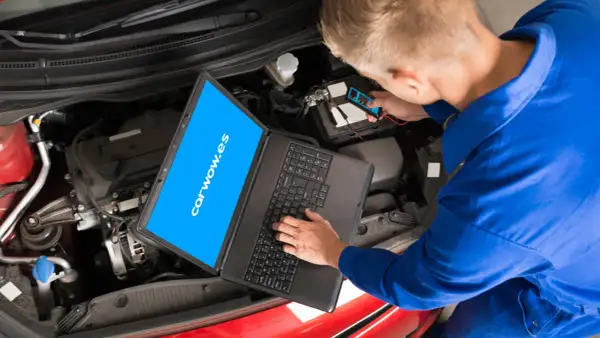 Mecánico revisa el motor de un coche con un portátil y un dispositivo de diagnóstico. El **stage** de la revisión es crucial para el **significado** del buen funcionamiento.