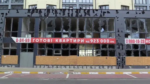 Uszkodzony budynek z banerem "GOTOWI KWARTRYRY від 923 000 ГРН". Zastanawiasz się, ile kosztuje mieszkanie na Ukrainie?