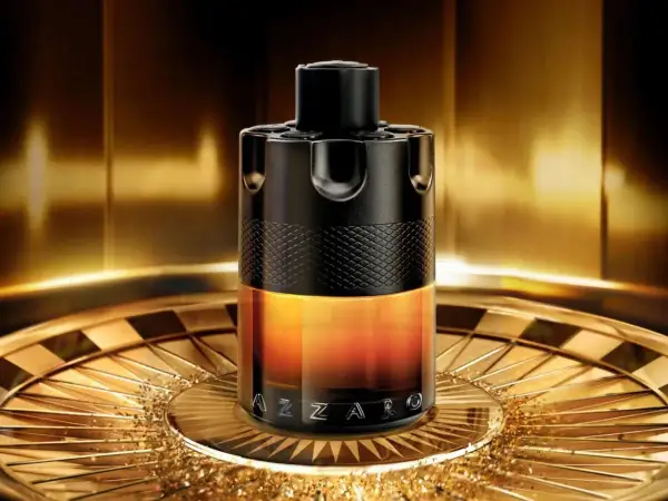 Elegancki flakon perfum Azzaro Wanted w odcieniach czerni i złota, stojący na ozdobnej tacy.