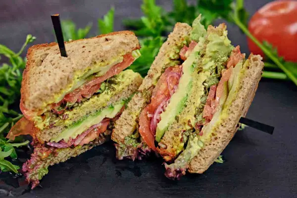 Tramezzini gusti freschi e colorati con avocado, pomodoro, cipolla rossa e insalata su pane integrale.