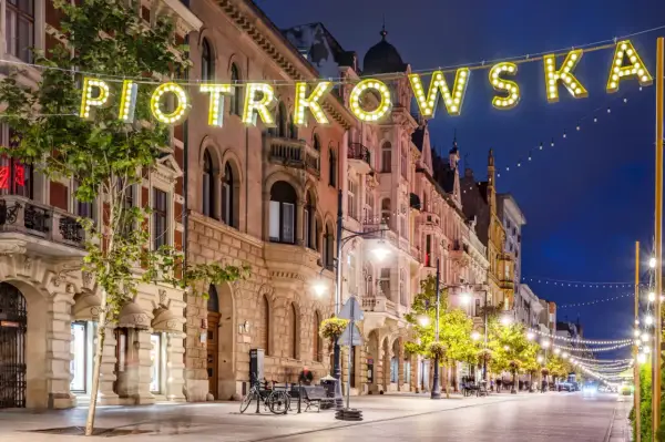 Ulica Piotrkowska nocą, iluminowana neonami i girlandami świateł. Idealne miejsce, by poczuć klimat Łodzi i zastanowić się, co zwiedzić w Łodzi.