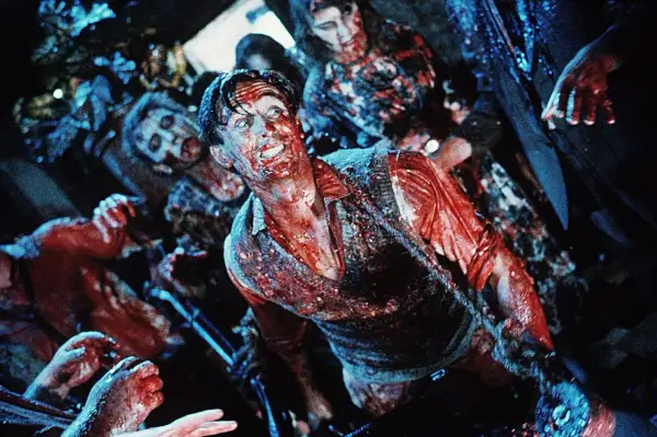 Krwawy mężczyzna otoczony przez zombie. Scena pełna grozy, idealna dla fanów **horrory 18+**.