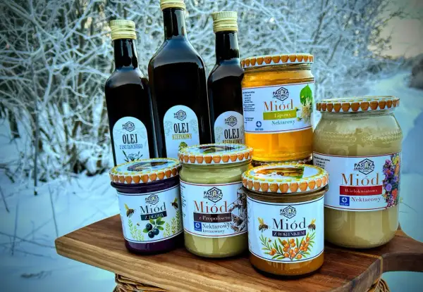 Słoiki z miodem i butelki z olejem na tle zimowego krajobrazu. Miód pitny trójniak ile procent? Sprawdź etykiety!