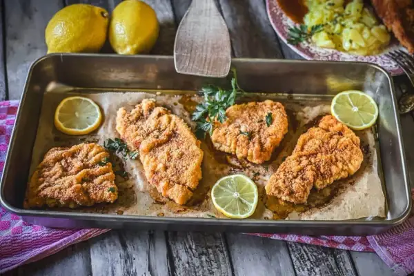 Vier saftige putenschnitzel im Ofen gebacken, garniert mit frischer Petersilie und Zitronenspalten.