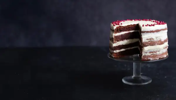 En läcker red velvet cake med lager av choklad och krämig frosting, dekorerad med röda pärlor.
