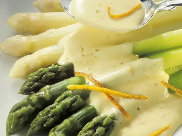 Frischer Spargel, weiß und grün, wird mit einer cremigen Sauce und Orangenzesten serviert. Perfekt zum Spargel kochen.