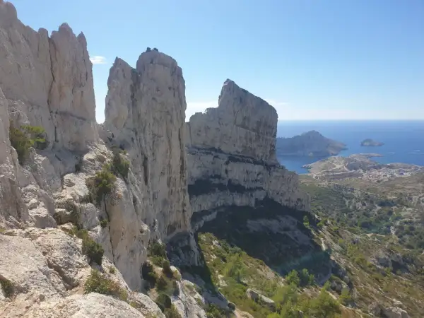 Vue spectaculaire depuis le pas de la demi lune, avec des falaises calcaires imposantes dominant la mer Méditerranée et un village côtier.