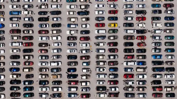 Wielki parking pełen europejskich marek samochodów, uporządkowanych w rzędy.
