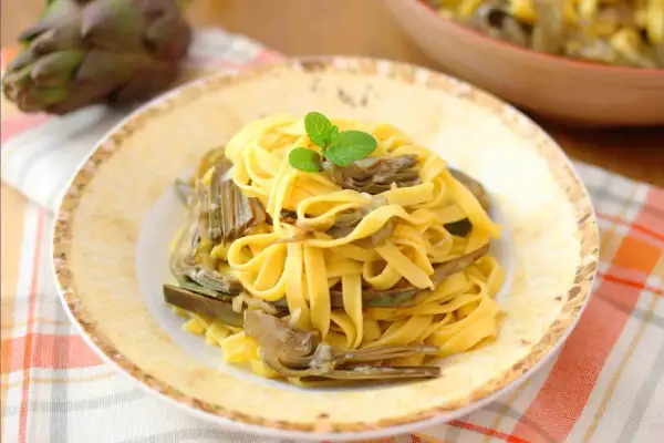 Tagliatelle fresche con carciofi teneri, guarnite con menta. Un piatto primaverile che celebra i sapori della terra.