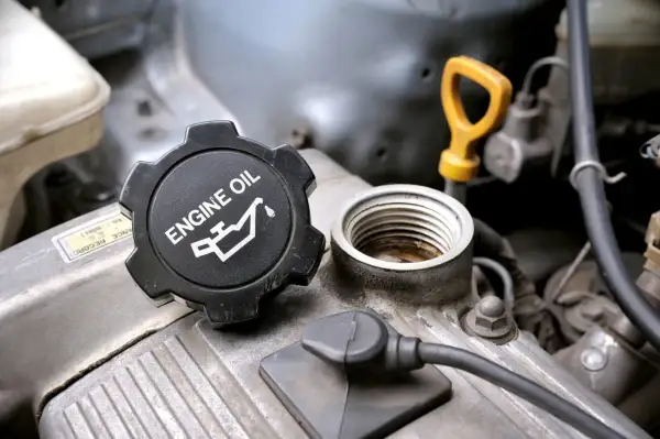 Korek silnika z napisem "ENGINE OIL" i symbolem. Pytanie: co ile wymiana oleju?