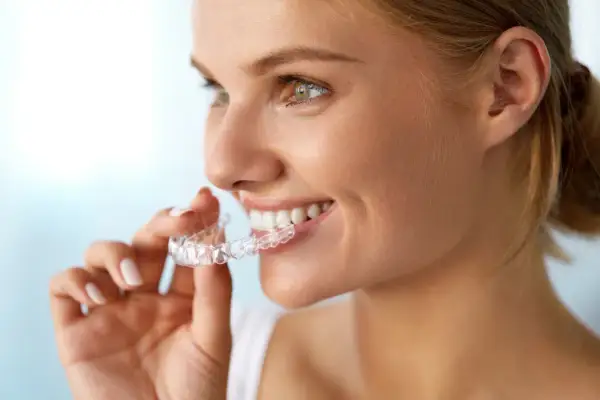 Donna sorridente mostra il suo invisalign indossato, un sorriso smagliante in arrivo.