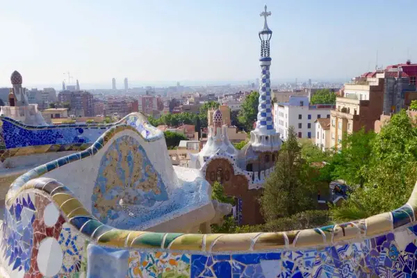 Bunte Mosaikbänke und Gaudís Märchenhäuser im Park Güell, eine der berühmtesten Barcelona Attraktionen, mit Blick auf die Stadt.