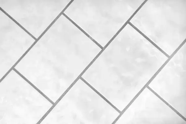 Białe, błyszczące płytki ułożone w geometryczny wzór. Precyzyjna rektyfikacja płytek zapewnia idealnie równe fugi.