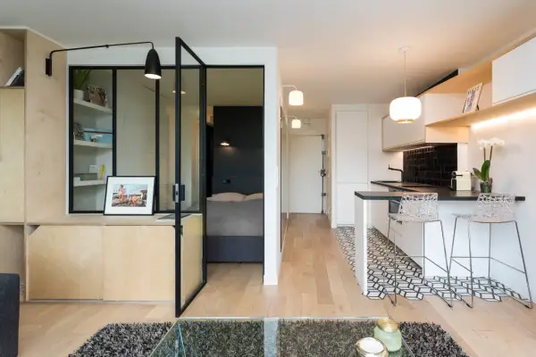 Interno di moderni mini appartamenti con zona giorno, cucina a vista e camera da letto separata da vetrata.