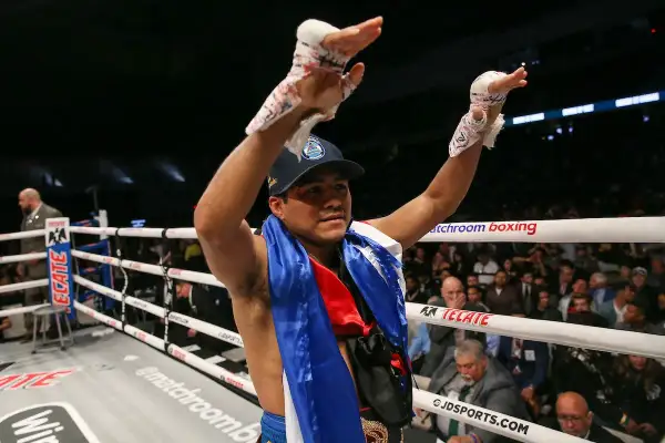 A victorious boxer, representing Nicaraguan pride, raises his taped hands in triumph in a packed arena.