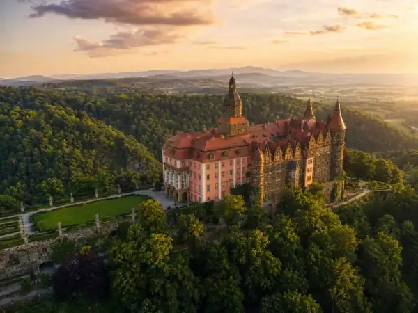 Zamek Książ, jedna z największych atrakcji Dolnego Śląska, w otoczeniu zielonych wzgórz o zachodzie słońca.
